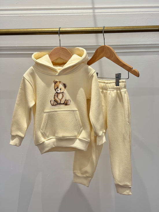 Children's beige hoodie and pants set with a teddy bear design on a white background