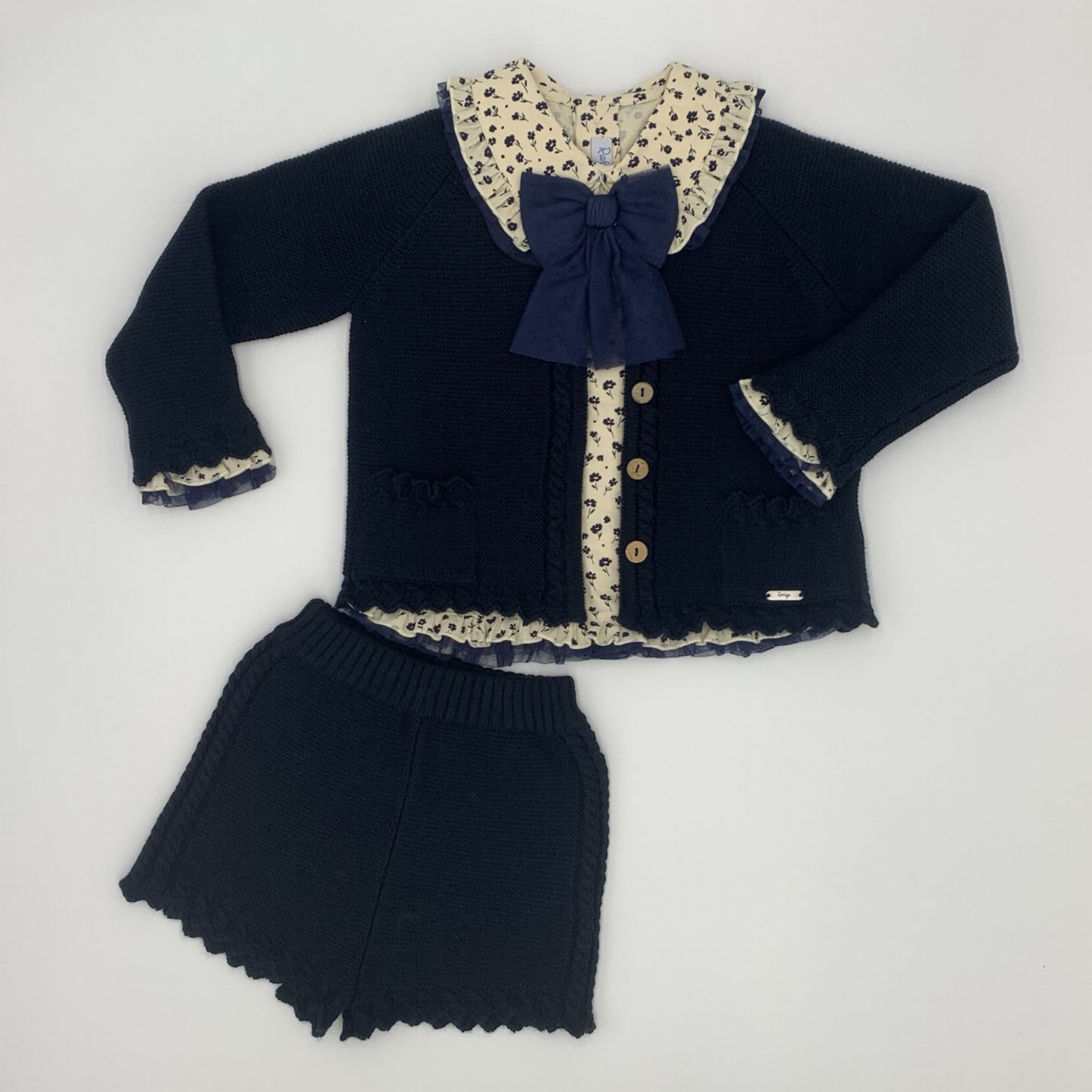 Rahigo girls outfit. Navy knitted shorts and matching cardigan and an ivory blouse with navy floral pattern 